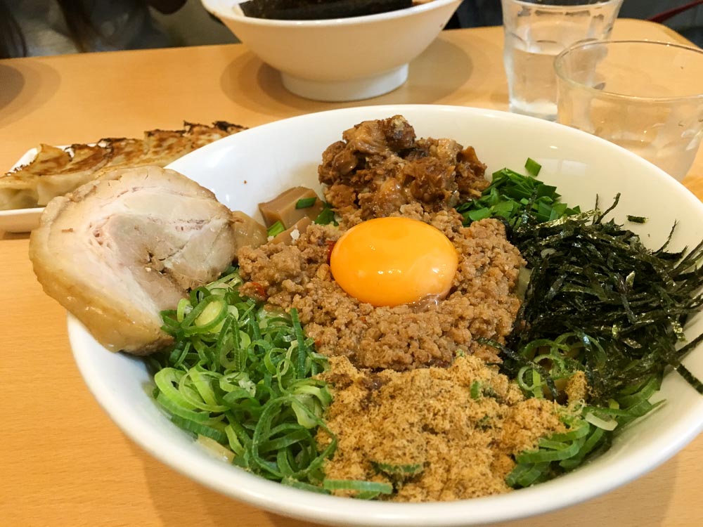 a bowl of ramen with generous toppings of egg, minced meat and spring onions - Osaka budget