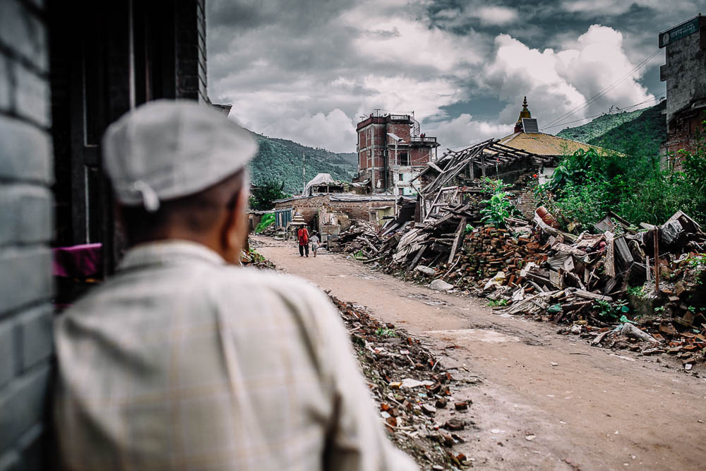 Man on street looks at wreckage on street, Nepal - Travel photojournalism