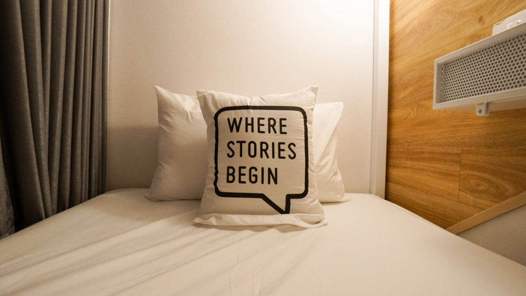 A pillow that reads "Where Stories Begin", in a bed at home