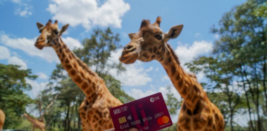 Holding Youtrip Card infront of Giraffes in Kenya---YouTrip Review Featured 2