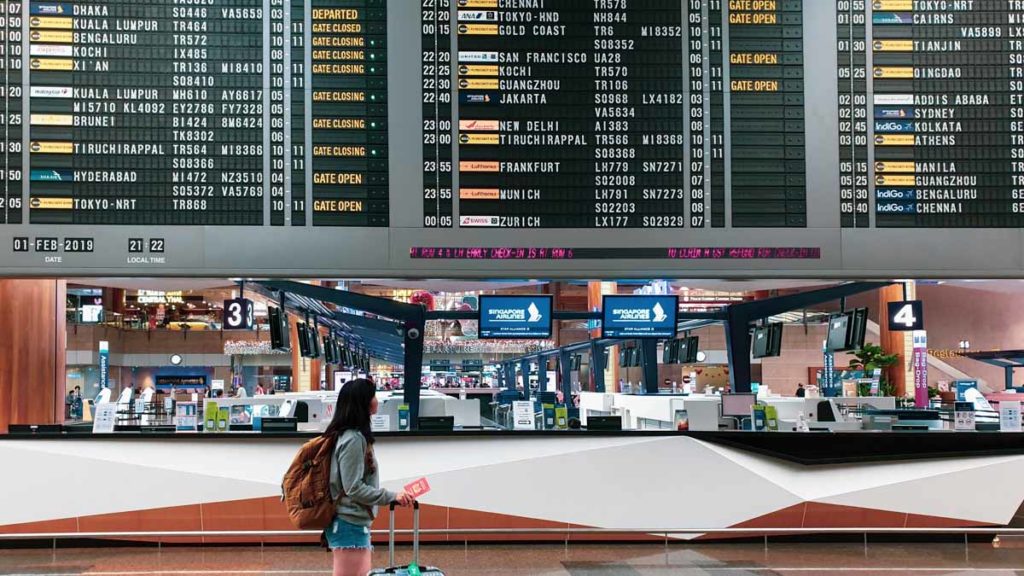 Singapore traveller at changi airport departure board - Singaporean students studying abroad