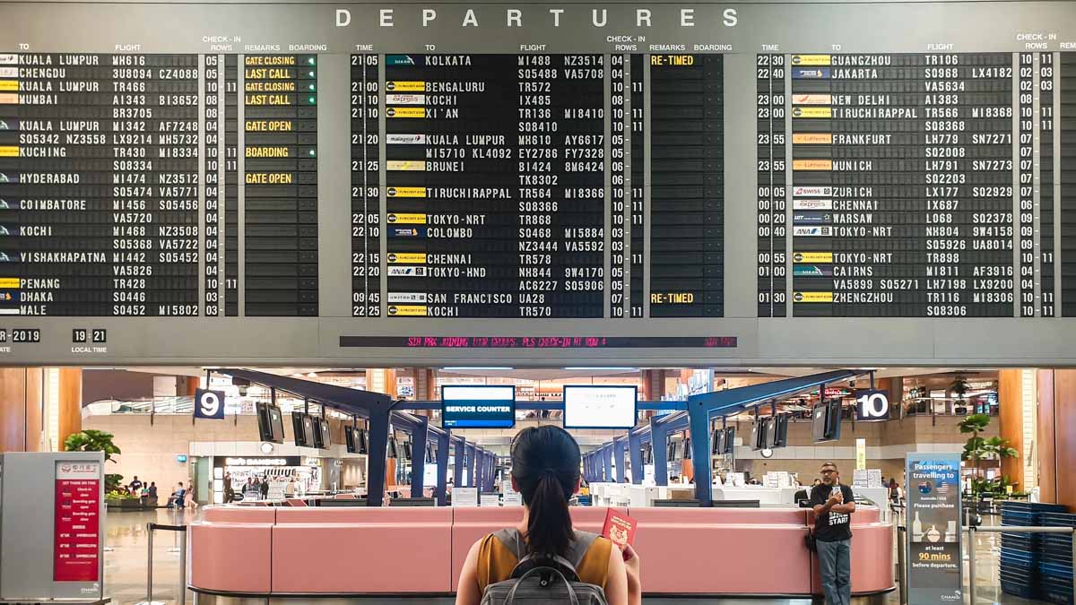 Traveller looking at flight information board at Singapore airport - Solo Travel Guide
