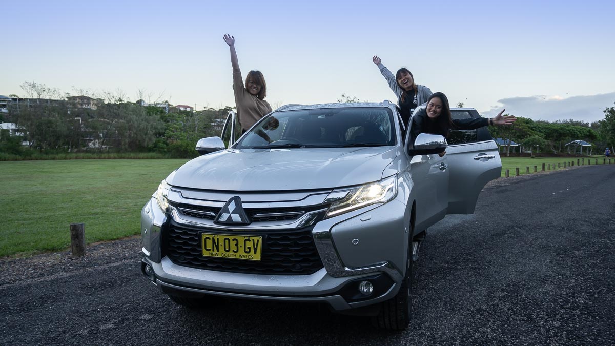 Group shot with car in the day - Solo Travel Guide