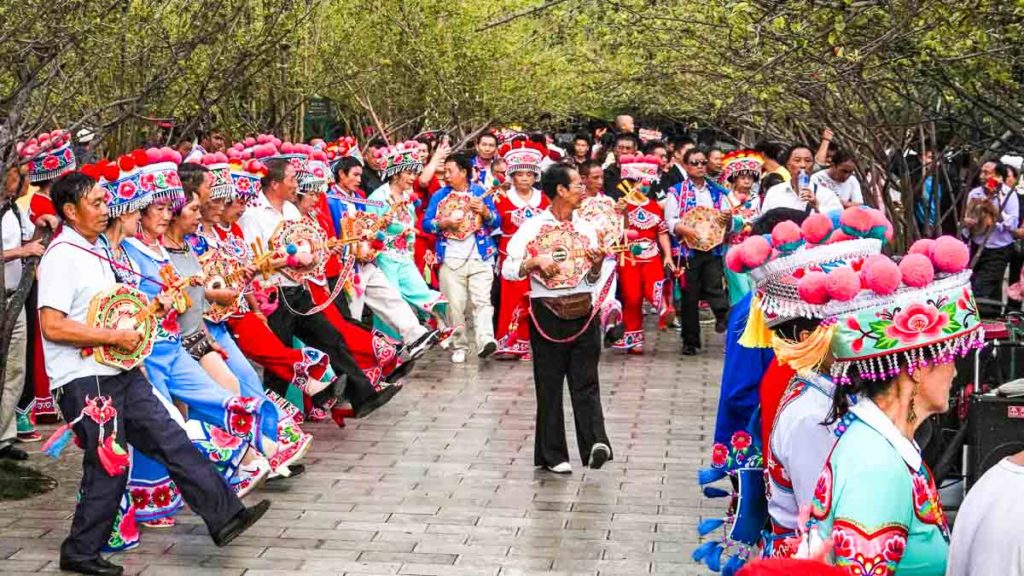 Locals in traditional ethnic costumes get togther at Cuihu green lake park - China Things to do in Kunming city