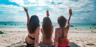 Girls on a beach facing the sea with drinks in their hands - Phuket luxury villas