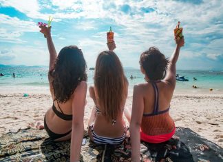 Travellers in Quarantine — 12 Satisfying Things to Do Before Your Next Adventure Girls on a beach facing the sea with drinks in their hands - Phuket luxury villas