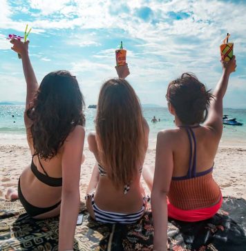 Girls on a beach facing the sea with drinks in their hands - Phuket luxury villas