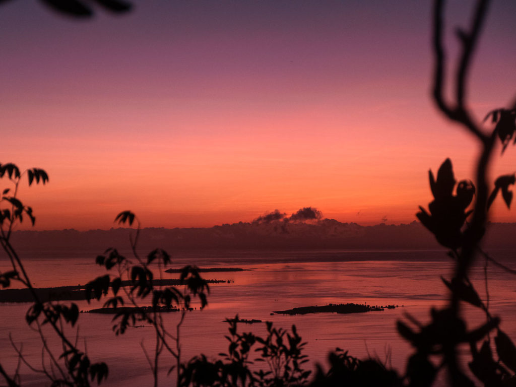 The Sun peaking over the horizon with a clear view of Honda Bay from Mount Magarwak - Puerto Princesa Itinerary 