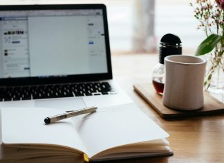The Ultimate Pre-Trip Planning Checklist — 12 Things to do Before Your Next Trip Featured - Laptop on Desk with Journal and Mug_