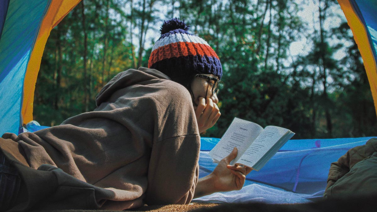 Person reading a book in a tent - Travel Books and Shows