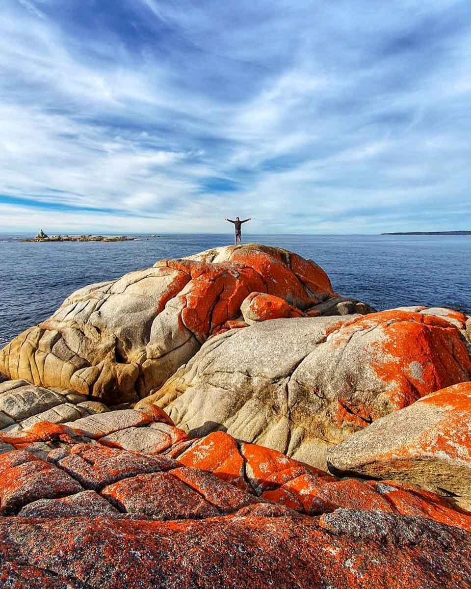 Person Standing on Orange Rocks Bay of Fires - Instagrammable Places to Visit in Tasmania Australia