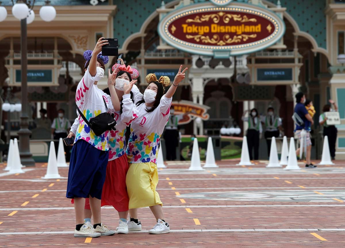 Visitors in Tokyo Disneyland with masks on - Theme parks reopen after COVID