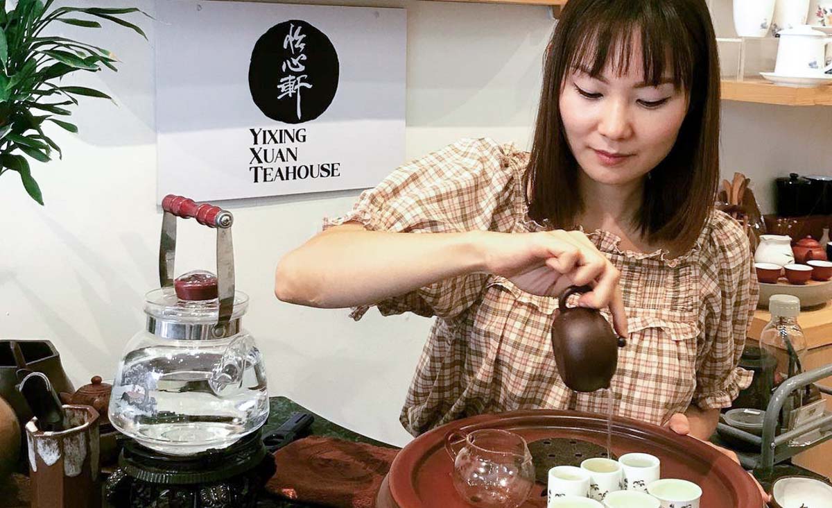 Woman pouring tea into cups at Yixing Xuan Teahouse