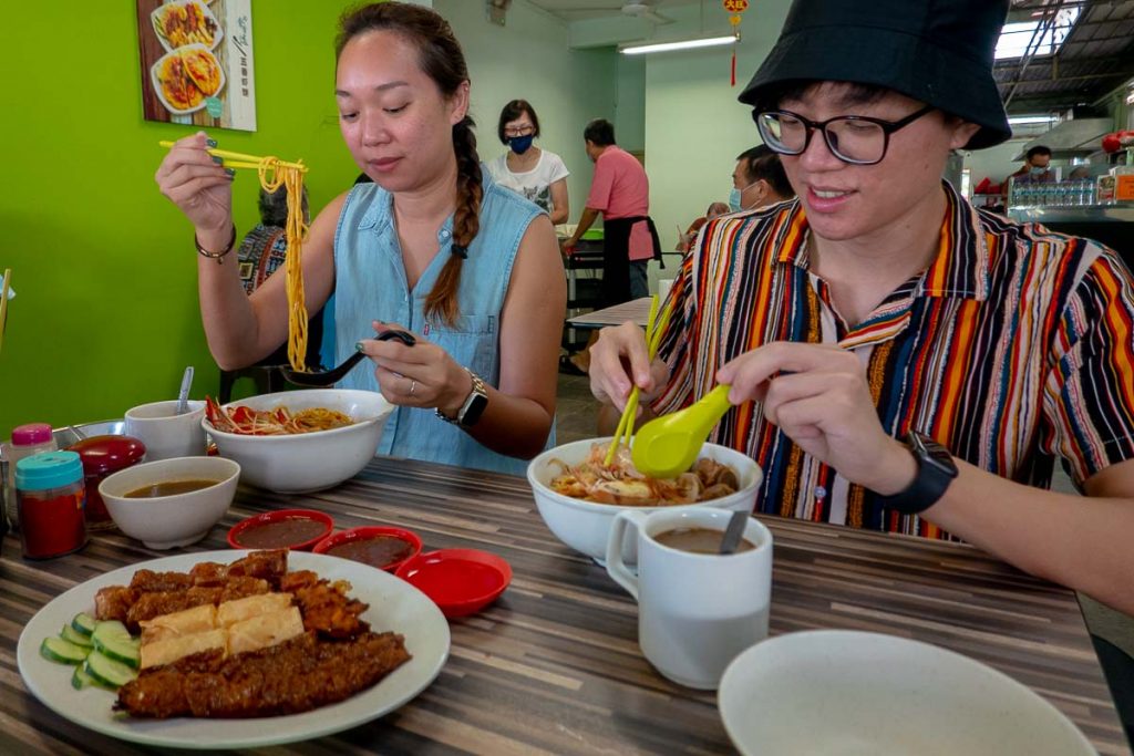 Friends eating prawn noodles at Beach Road Prawn Mee - Best things to eat in SG