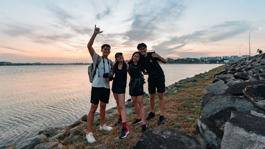 Four friends standing in front of a lake posing - Night Cycling Singapore