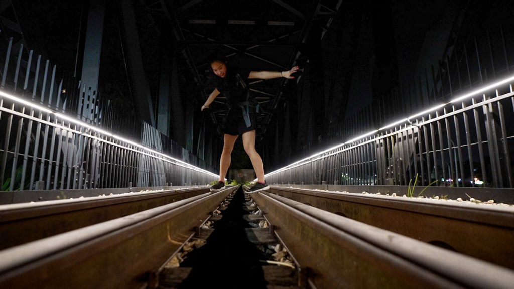 Girl balancing on train tracks - Night Cycling Singapore