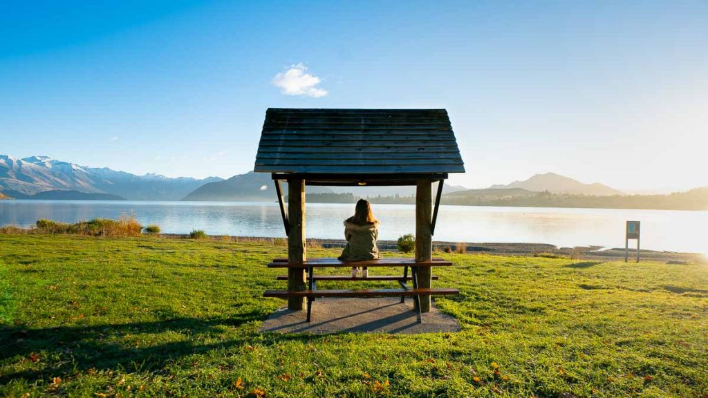 Girl sitting at Lake Wanaka lakefront - New Zealand South Island Itinerary