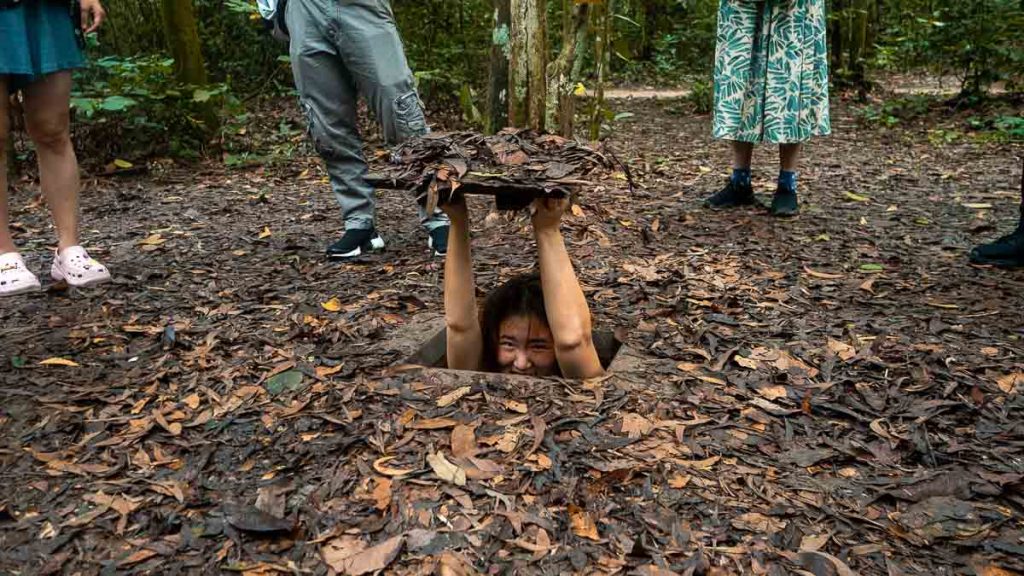 Girl squeezing through the cu chi tunnel entrance - Things to do in Ho Chi Minh City