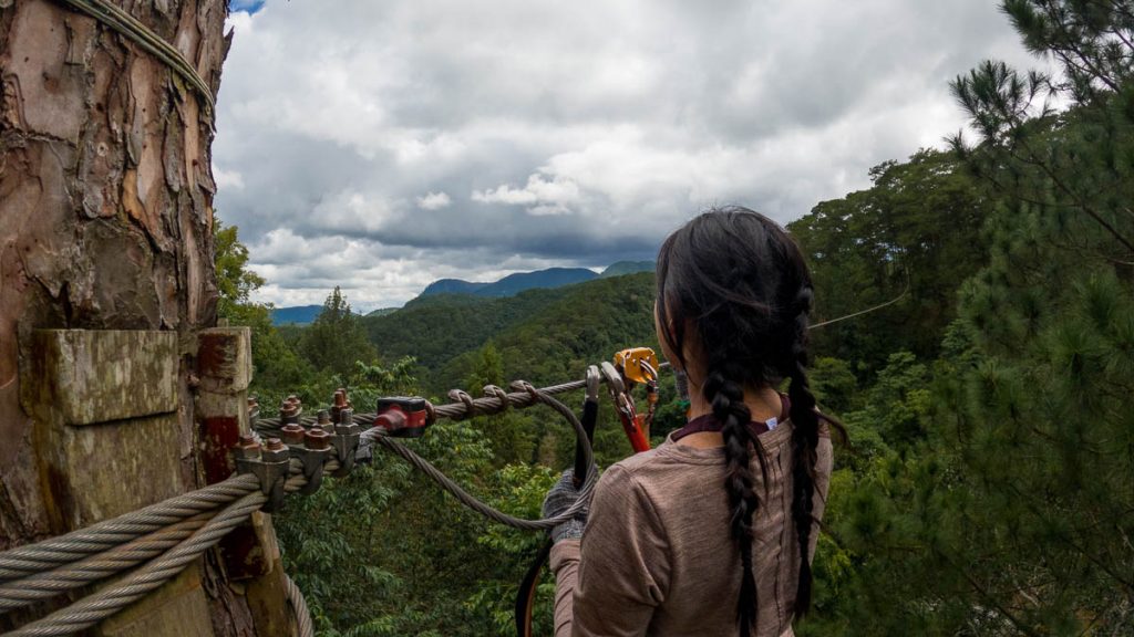 Girl holding onto zipline while looking at view of Datanla high rope course