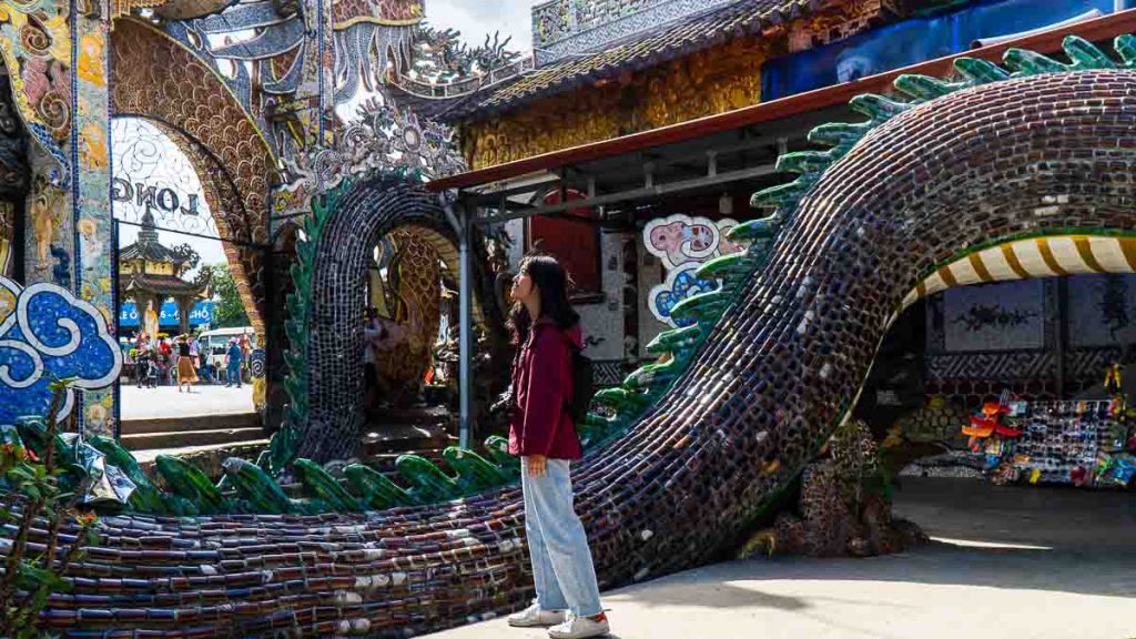 Girl standing in front of dragon sculpture at Linh Phuoc Pagoda Da La
