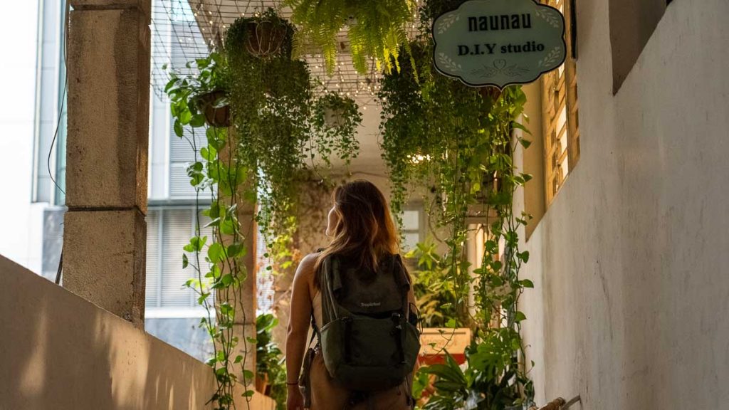 Girl wandering through the plant-lined corridor of the Cafe Apartments - Things to do in Ho Chi Minh City