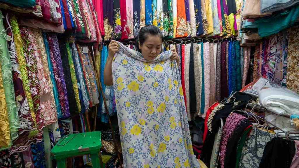 Lady holding floral fabric in a fabric store at Ben Thanh Market- what to do in ho chi minh city