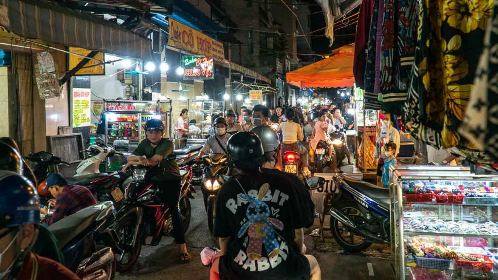Motorcycles cramped in a street lined with food carts - Things to do in Ho Chi Minh City