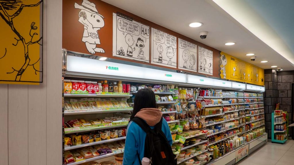 girl browsing though snacks at snoopy 7-11 - taipei itinerary