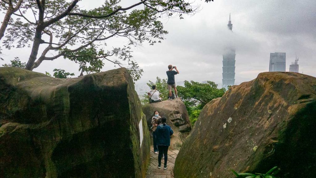 people climbing rocks to take a picture at xiangshan elephant mountain - taipei itinerary