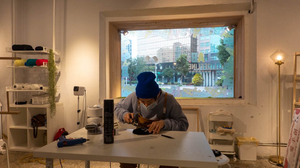 An artist cutting of loose ends from his handmade tufted rug - taipei itinerary