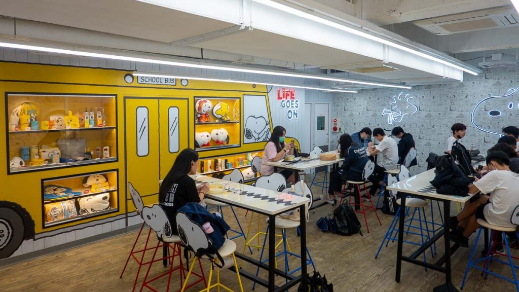 teenagers sitting in seating area in snoopy 7-11 - things to do in taipei 