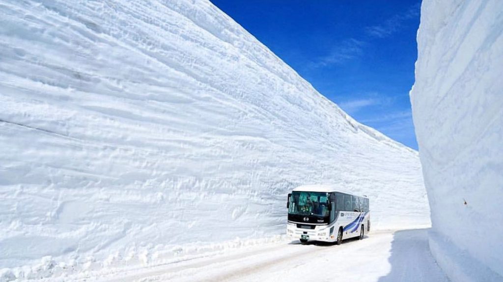 Bus driving through a snow wa;;