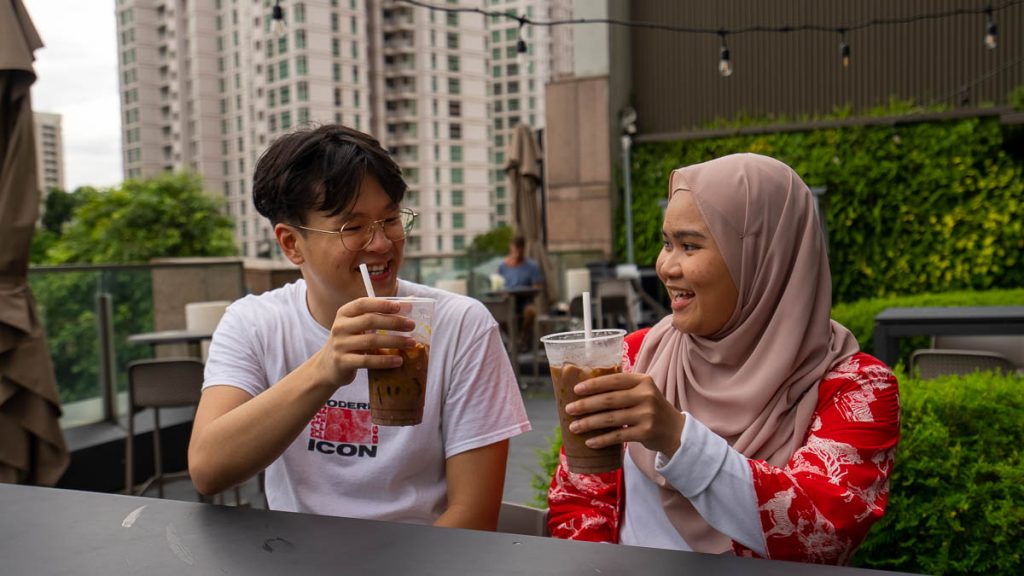 two friends having an iced milo at Food Junction Great World's rooftop dining - thomson-east coast line