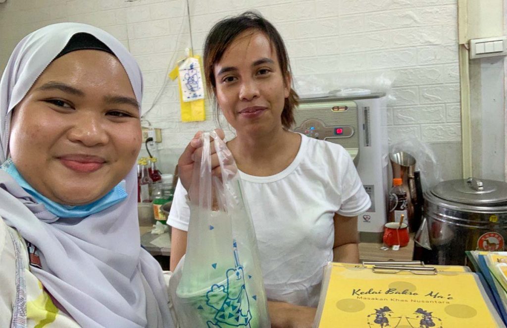 girl in hijab holding up chendol with a shop owner in kedai bakso ma'e - Solo female travel