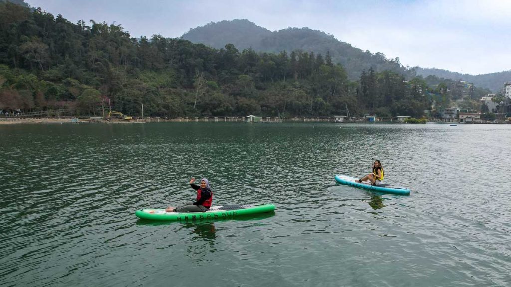 2 people sitting on stand up paddle boards in sun moon lake - things to do in sun moon lake