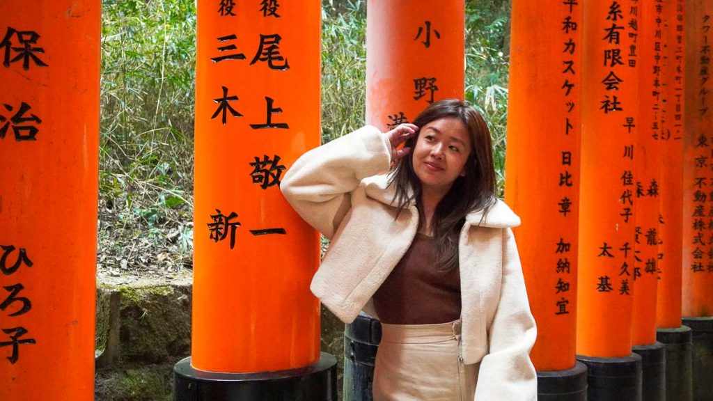 Girl leaning against a torii gate at Fushimi Inari Taisha - Travel Outfit Ideas