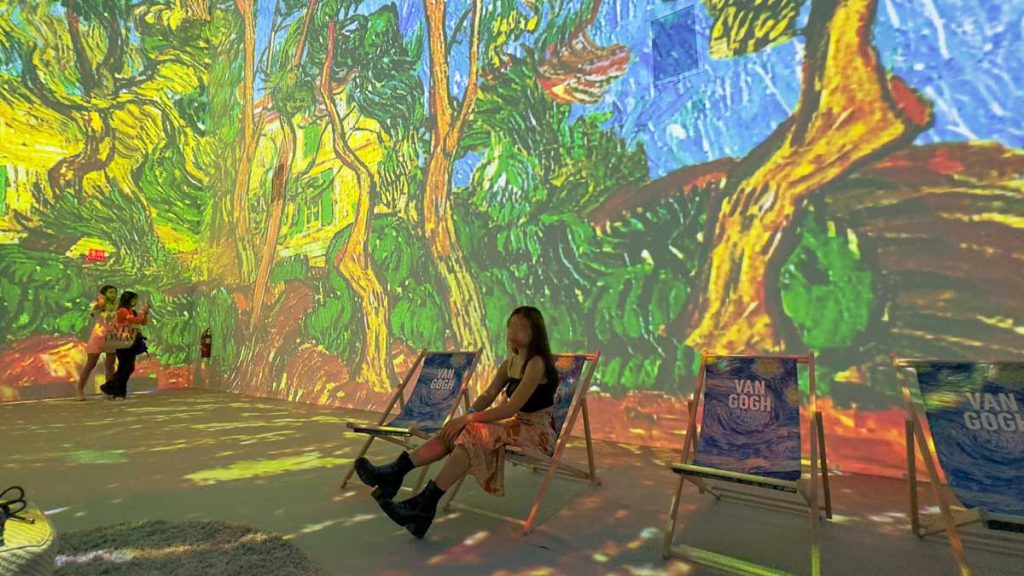 Girl sitting on chair and looking at Van Gogh's art - Things to do in Singapore March 2023