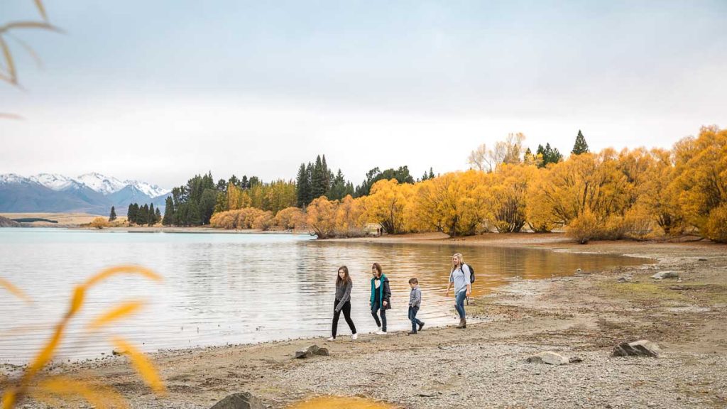 Family walking along Lake Tekapo in South Island - NZ Off-peak Guide