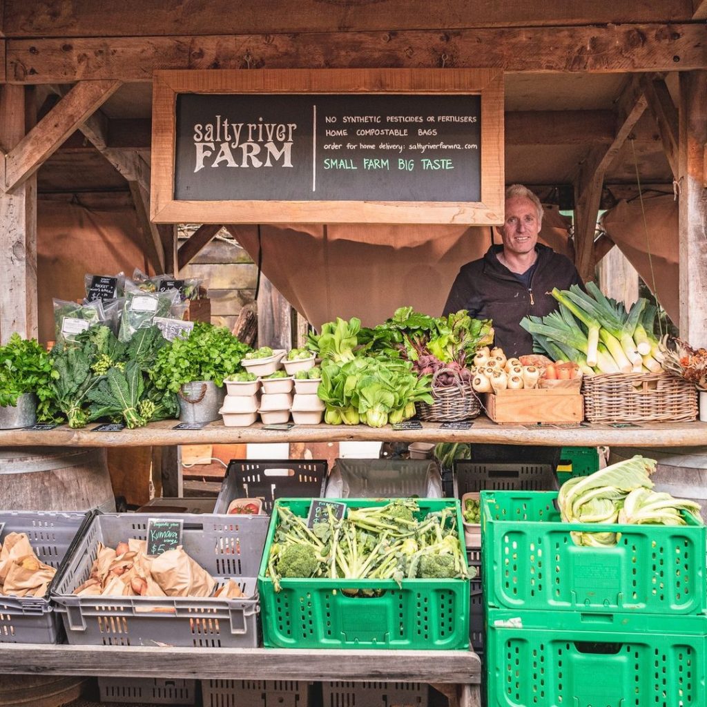 Man selling vegetables at his farmers market stall at Matakana Village