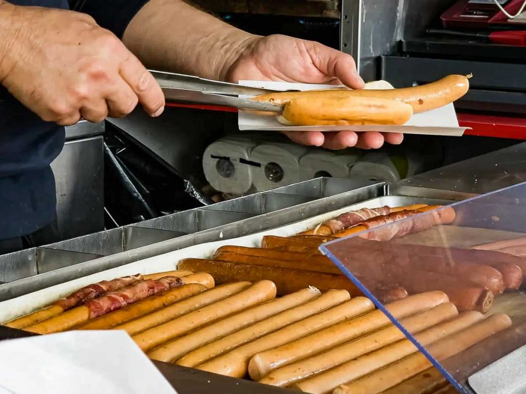 man assembling hot dogs from byens polser - cultures explained
