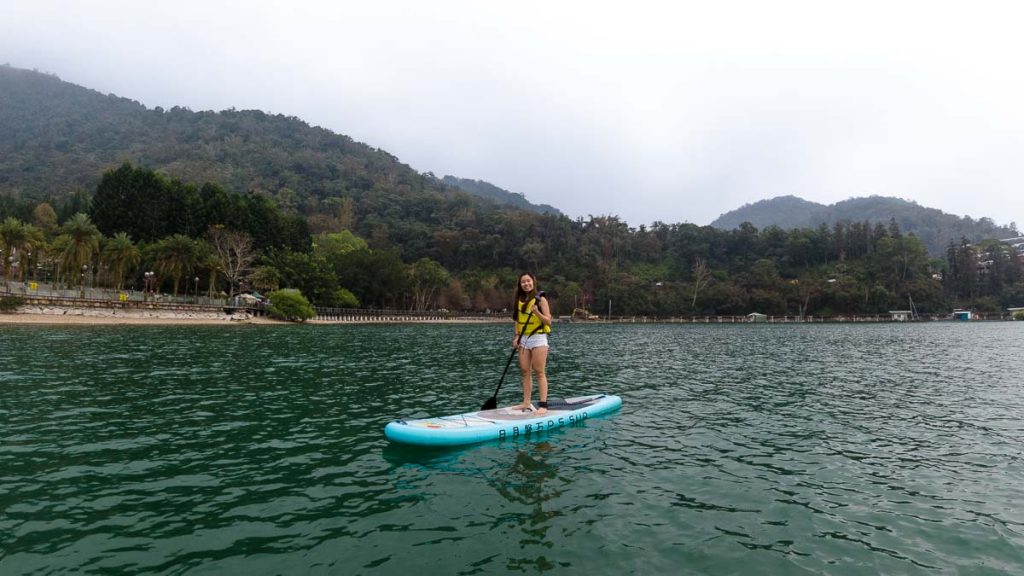 girl standing on stand-up paddle board in sun moon lake - things to do in taiwan