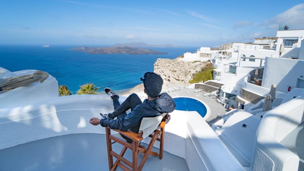 Man on Volcano View Hotel Balcony - Greece Bucket List