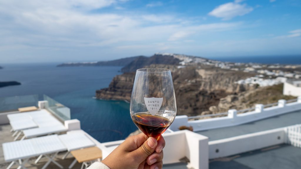 Girl holding up a glass of Vinsanto Wine in Santorini - Things to do in Greece