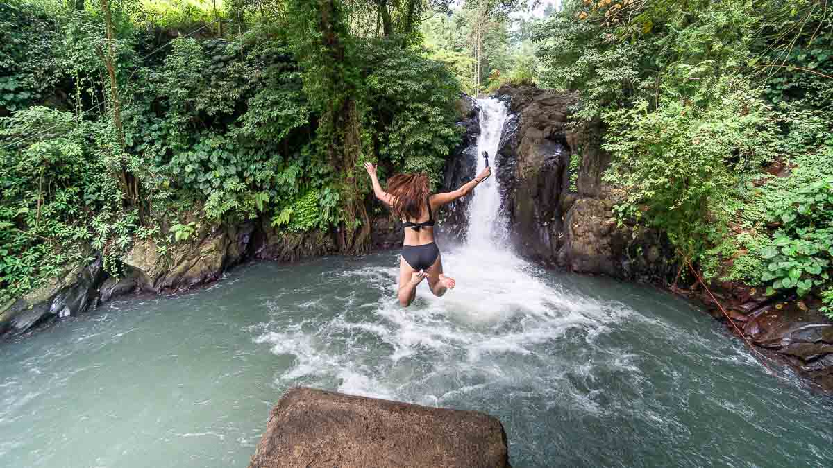 Woman jumping off Kroya Waterfall - Bali Itinerary