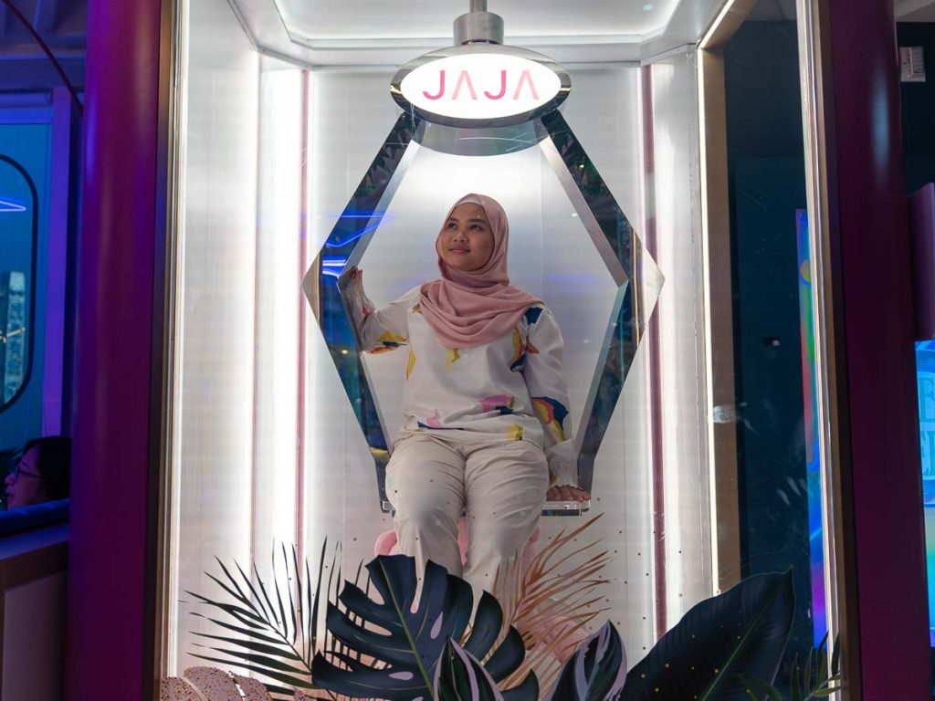 girl sitting in a life sized claw machine at jaja vegetarian restaurant - cafes in hong kong