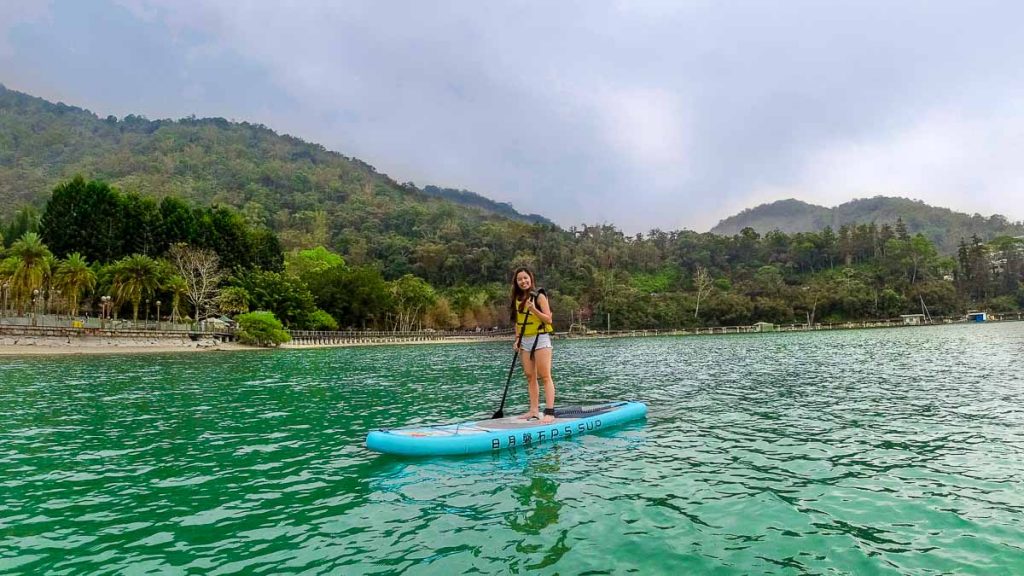 girl standing on stand-up paddle board in sun moon lake - things to do in taiwan