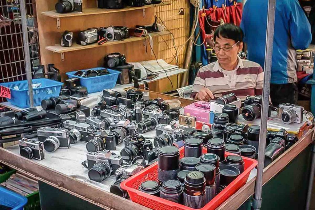 Man sits, selling used cameras at stall -  Things To Do in Hong Kong, Sham Shui Po