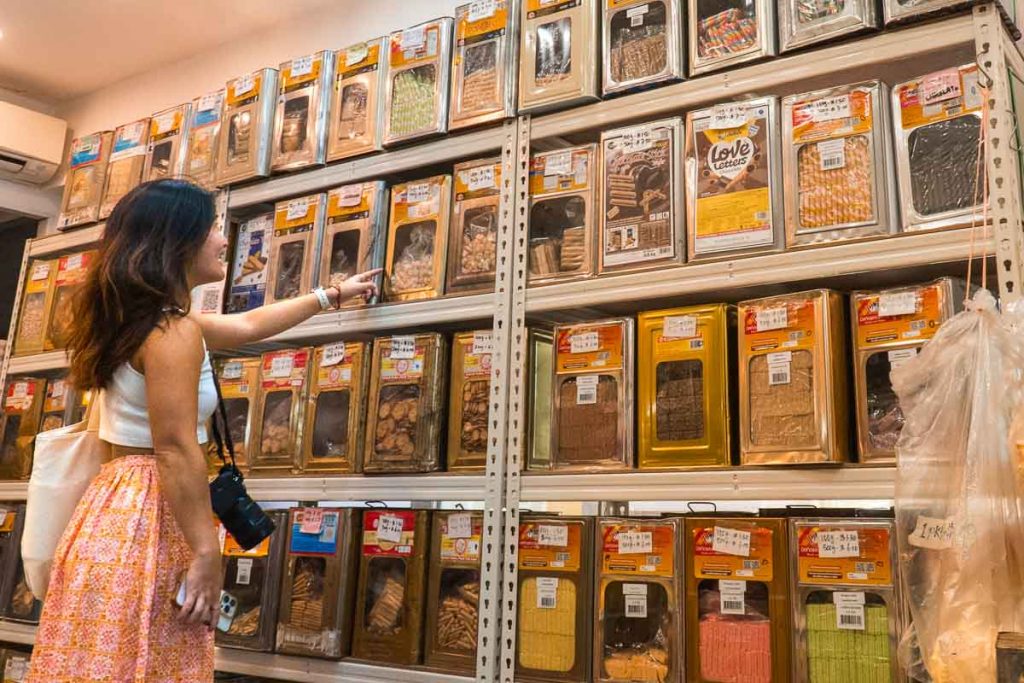 Girl pointing at traditional biscuit tin rack at Seah's Biscuit Shop - Things To Do In Ang Mo Kio