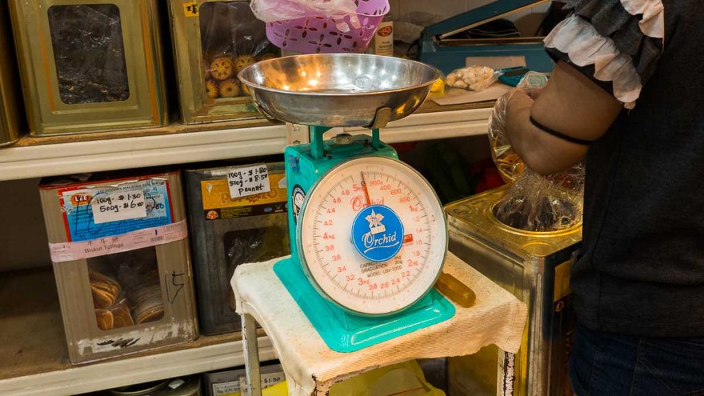 Lady uses weighing machine to package biscuits at Seah's Biscuit Shop - Things To Do In Ang Mo Kio
