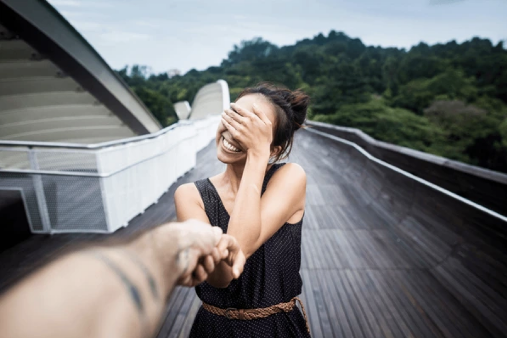Singaporean girl smiling, covering her eyes while taking partner's hand at henderson waves - Boutique Hotels in Singapore